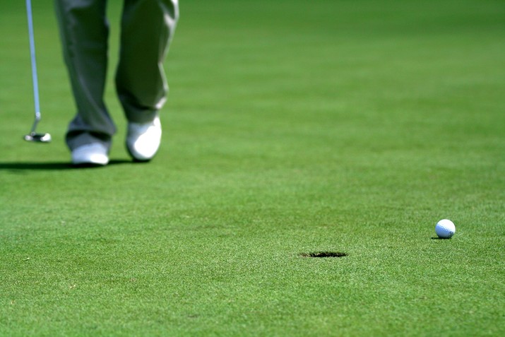 Golfer Walking Towards Ball Near Hole